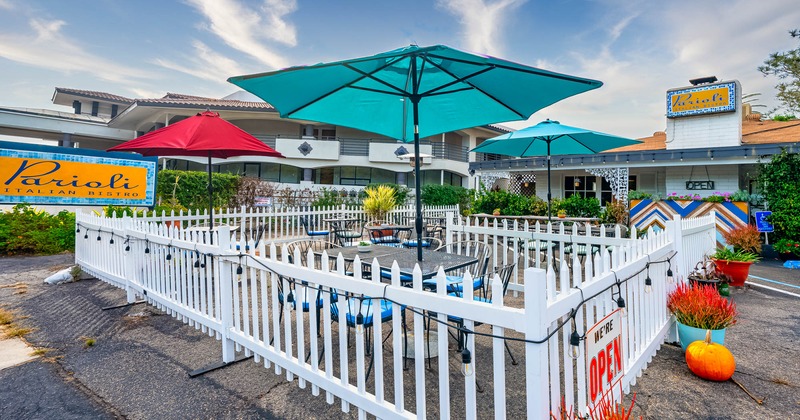 Exterior, patio, white fence, tables and chairs, cyan and red parasols