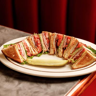 Club sandwich slices served with a pickle spear.