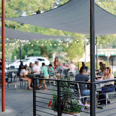 People dining outdoors under shade sails and string lights.