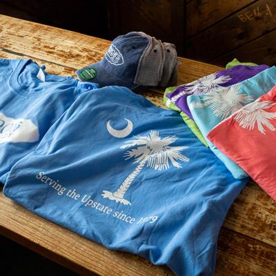 Colorful t-shirts with a palm tree and crescent moon design and a denim cap.