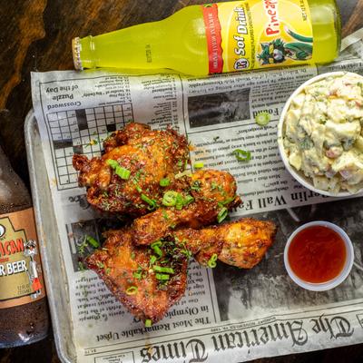 Sticky chicken with a side of coleslaw, accompanied with soft drinks.