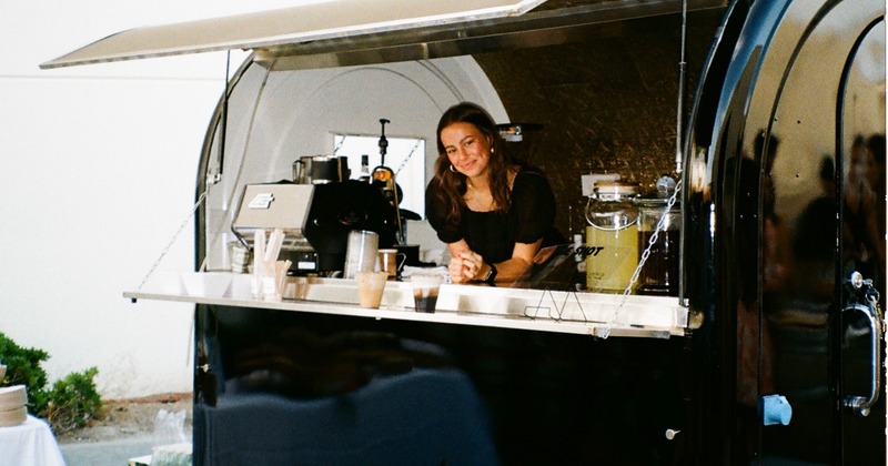 Shot of a coffee cart with a smiling coffeehouse employee