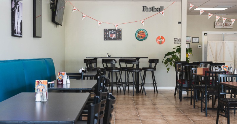 Casual dining area - tables, chairs, booth seating and sports-themed wall decorations