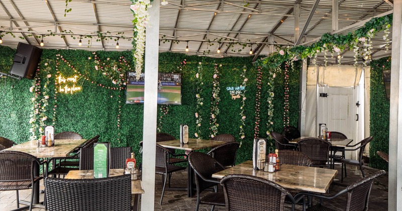 Covered outdoor patio, seating area with artificial green hedge walls