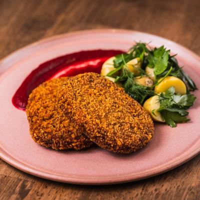 Crispy chicken cutlets served with a side salad and a red sauce.
