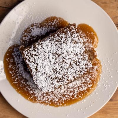 Sticky date cake topped with powdered sugar and brown butter caramel sauce.