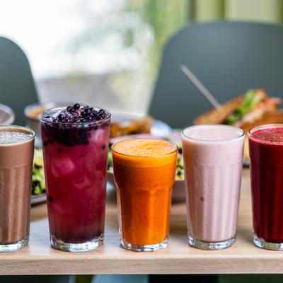 Variety of freshly prepared smoothies and juices displayed on the table.