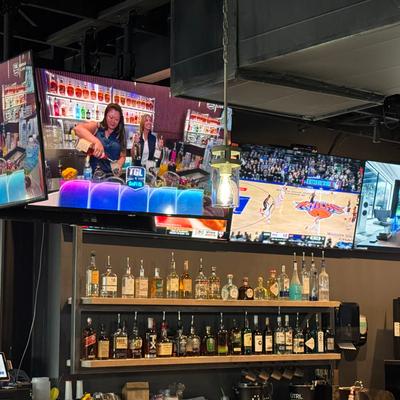 Shelves with bottles and flat screens.