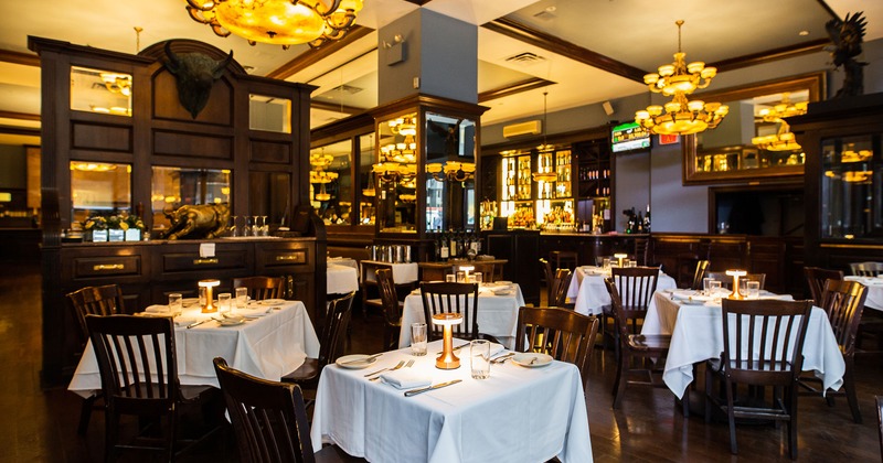 Interior, table and seating arrangement, tables with white cloths, tableware, and silverware