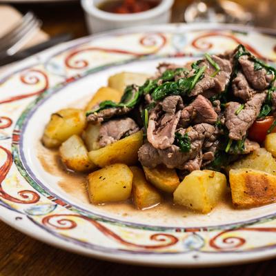 Beef slices with oregano, arugula & cherry tomatoes atop roasted potatoes.