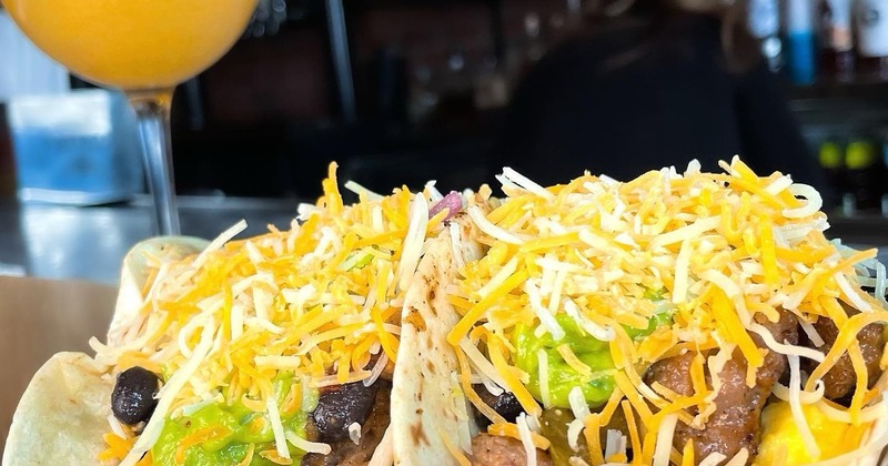 Two tacos on a plate and a glass of orange drink