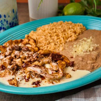 Grilled chicken and chorizo with cheese sauce, refried beans, and seasoned rice.