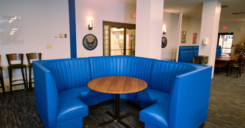 A blue U-shaped booth with a round wooden table in a cafe setting