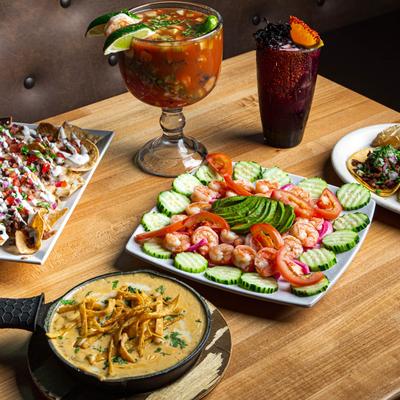 Mexican appetizers including shrimp, nachos, cheese dip, shrimp cocktail, and hibiscus margarita.