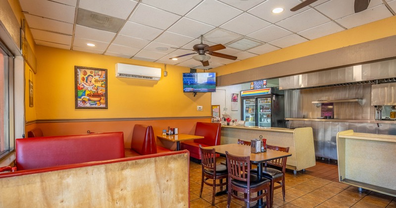 Cozy restaurant interior with red booths and wooden chairs against yellow walls