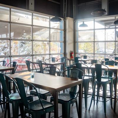 Interior, tables and chairs in front of large windows.