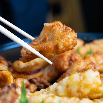 Chopsticks holding a piece of fried culiflower.