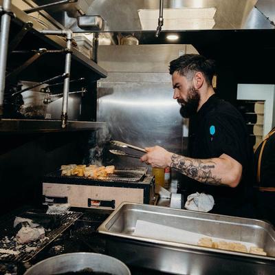 Kitchen staff cooking on griddle.
