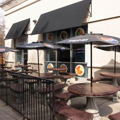 Outdoor patio seating with tables and black umbrellas.
