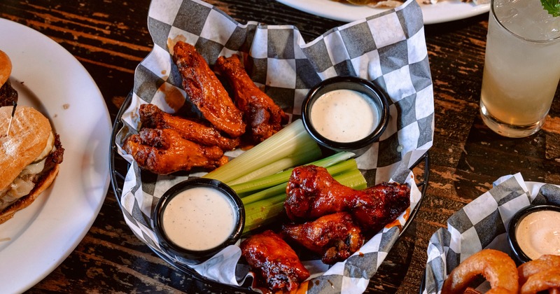 Basket of wings served with celery sticks and two cups of dipping sauce