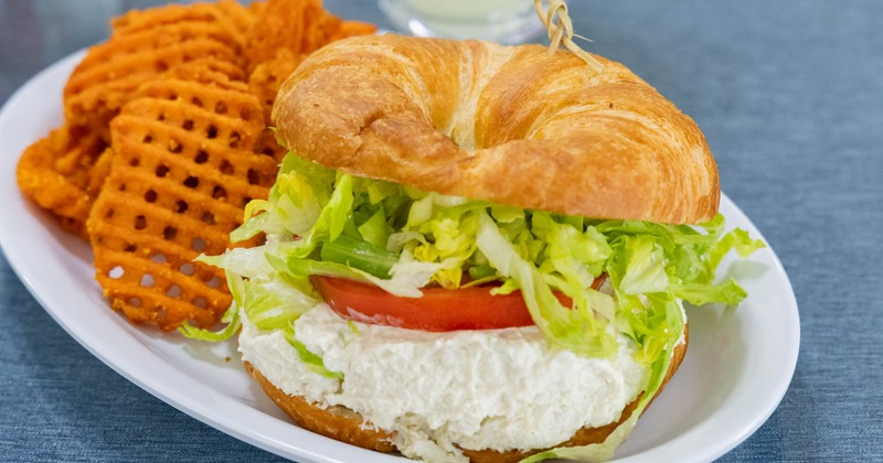 Chicken salad sandwich served on croissant with waffle fries on the side