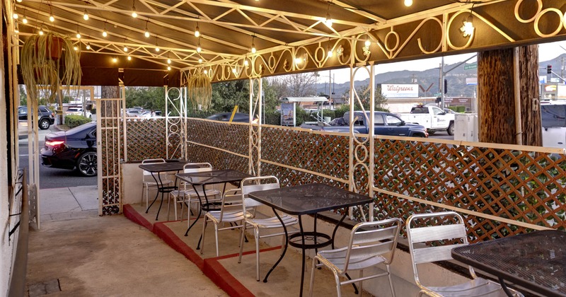Exterior, covered patio, seating area, metal aluminum chairs and metal tables for two
