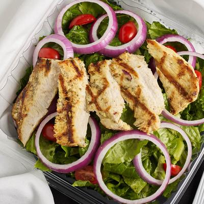 Grilled chicken salad with red onion rings, cherry tomatoes, and lettuce.