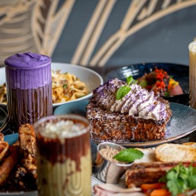 Assorted dishes and latte beverages spread on a table.