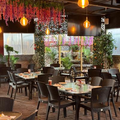 Indoor dining area decorated with hanging floral displays and greenery.