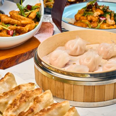 Dumplings in a bamboo steamer beside appetizers.