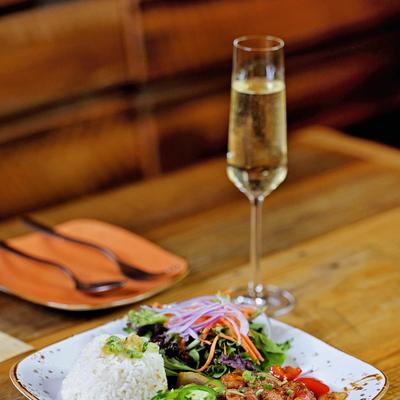 A plate of rice and salad accompanied by a glass of champagne.