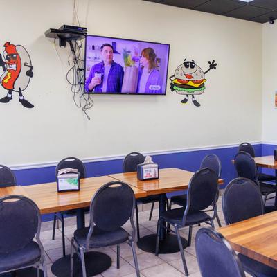 Interior, part of dining area, tables and chairs, a TV and mural decorations.