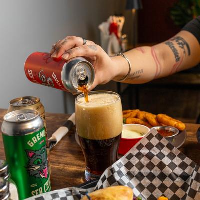 Dark beer being poured into glass at the table.