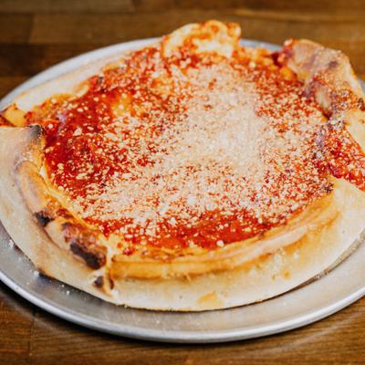Individual Chicago-style deep-dish pizza topped with rich tomato sauce and grated cheese.