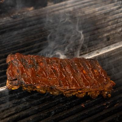 A rack of ribs smoking on a grill.