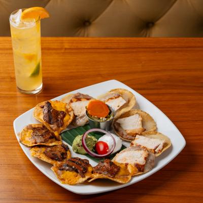Fajita nachos, served alongside cocktail in collins glass.