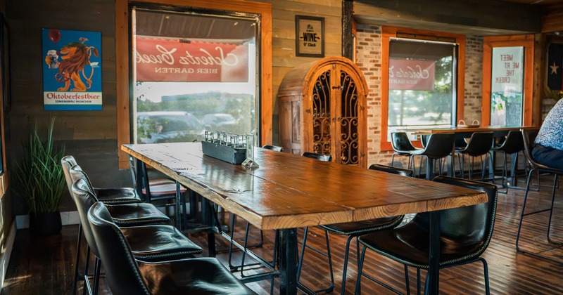 Rustic design of interior seating area with long table for eight guests with upholstered high stools