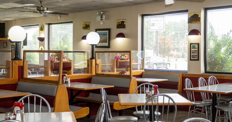 A diner with gray booths, wooden tables, large windows allowing natural light.