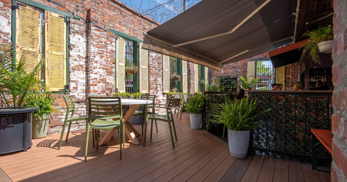 Outdoor patio with green chairs, round table, and potted plants