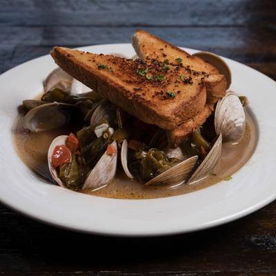 Drunken Steamed Clams topped with two slices of garlic bread.