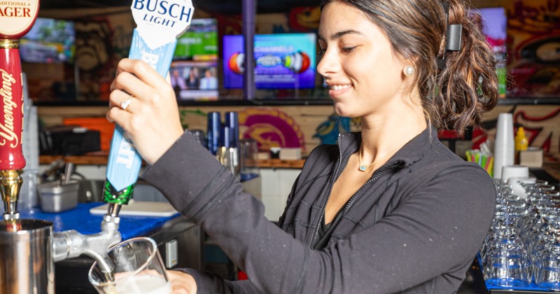The bar, the barmaid, pours beer