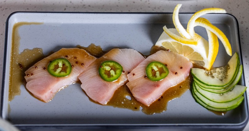 Yellowtail Sashimi garnished with jalapeño slice, sliced cucumber and carved lemon