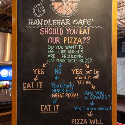 A blackboard writing explaining why a guest should eat pizza.