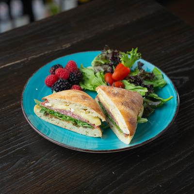 Brie sandwich served with salad and fresh berries.