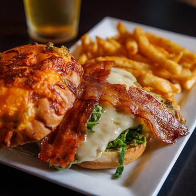 Chicken sandwich, with bacon, cheese guacamole, lettuce, and fries.