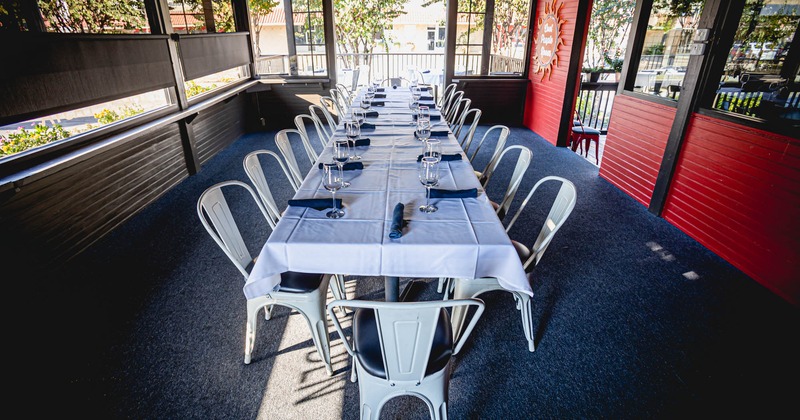 Private room, a long table with white table cloth, glasses and rolled napkins