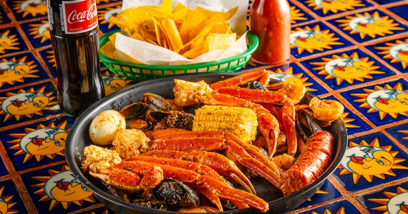 Cajun Seafood Boil served alongside tortilla chipa and bottle of soda