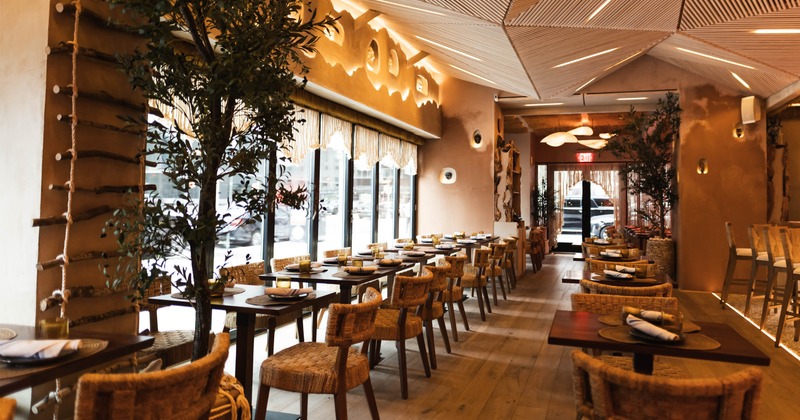 Restaurant interior with wooden tables, woven chairs, and geometric ceiling design
