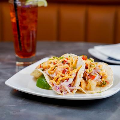 Grilled shrimp tacos served with a cold drink.