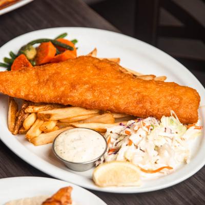 Fish and fries served with tartar sauce, coleslaw, lemon wedge, and veggies.